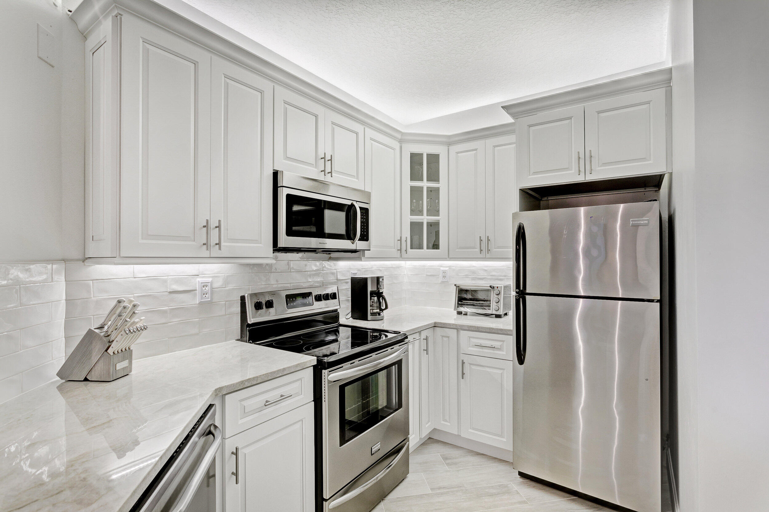 500 Uno Lago Drive, Unit 402 Juno Beach, FL 33408 - Photo 9 of 39 a kitchen with white cabinets and white appliances