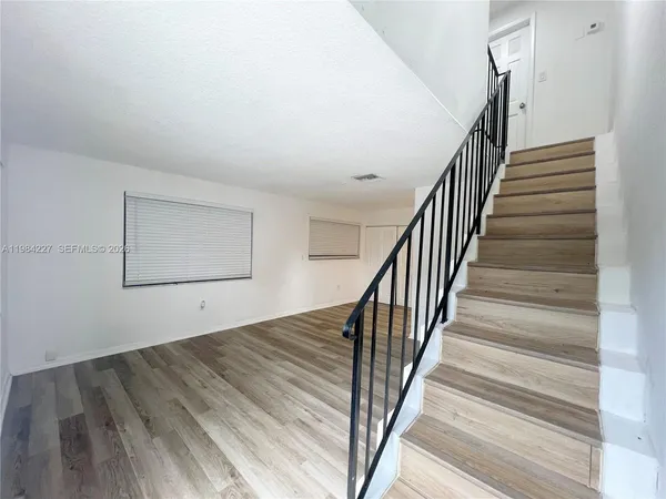 a view of staircase with wooden floor and white walls