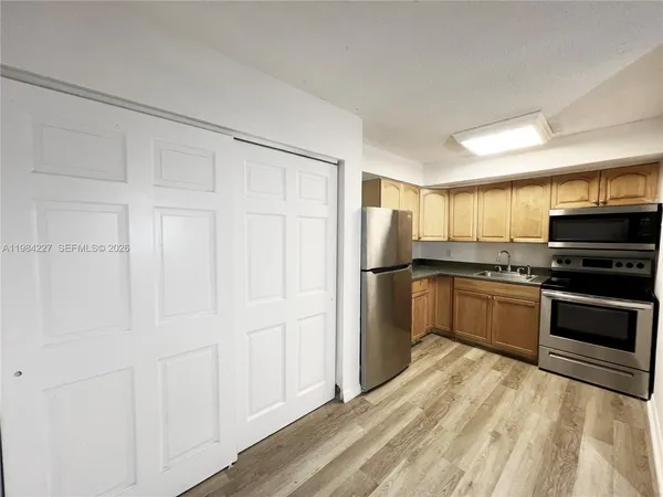 a kitchen with granite countertop a refrigerator and a stove top oven