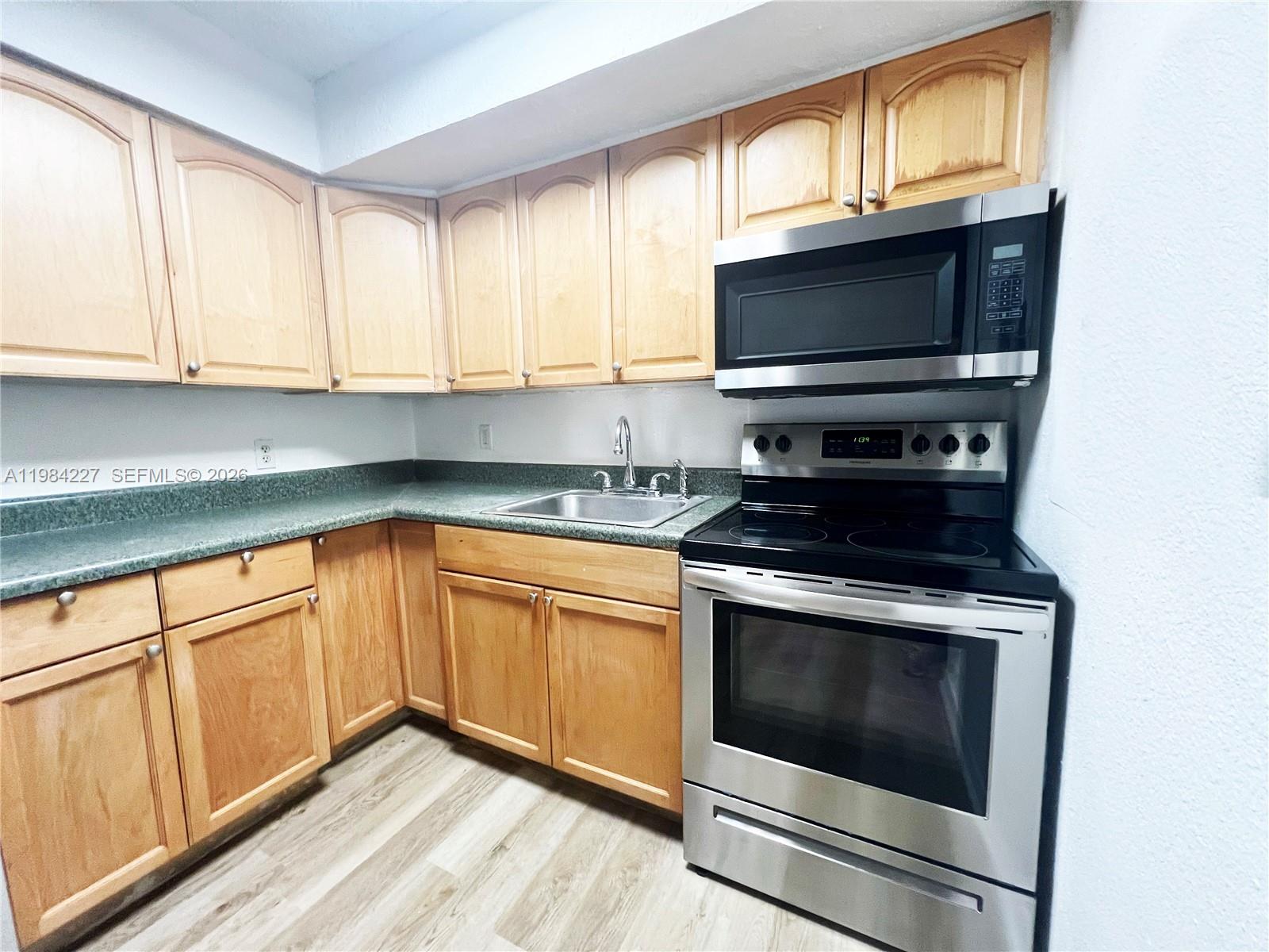65 Northeast 59th Street, Unit 2 Miami, FL 33137 - Photo 6 of 14 a kitchen with granite countertop a stove a microwave and a sink