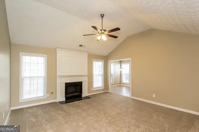 an empty room with windows and fireplace