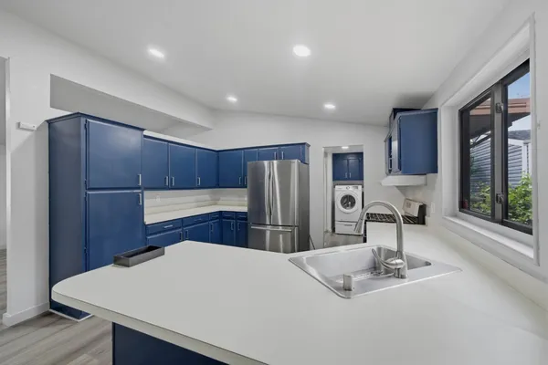 a kitchen with stainless steel appliances granite countertop a refrigerator a sink dishwasher a stove and white countertops with wooden floor