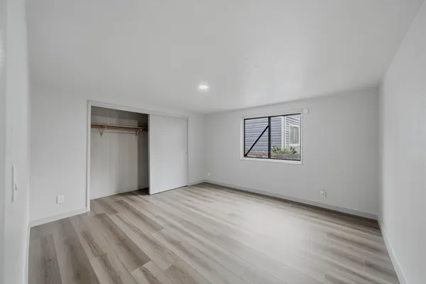 a view of an empty room with wooden floor and closet