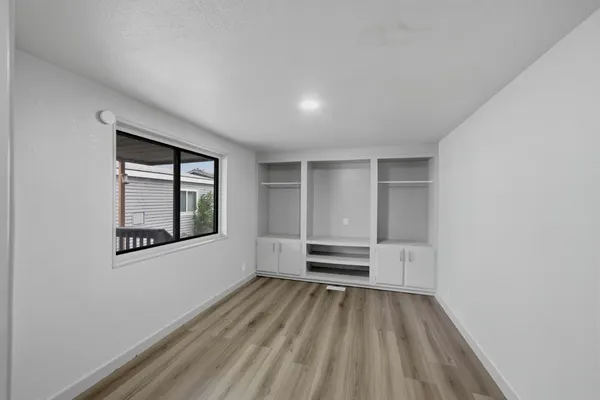 a view of an empty room with wooden floor and a window