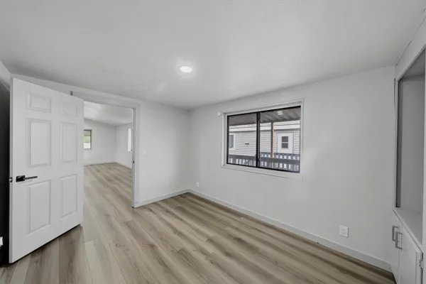 a view of an empty room with wooden floor and a window