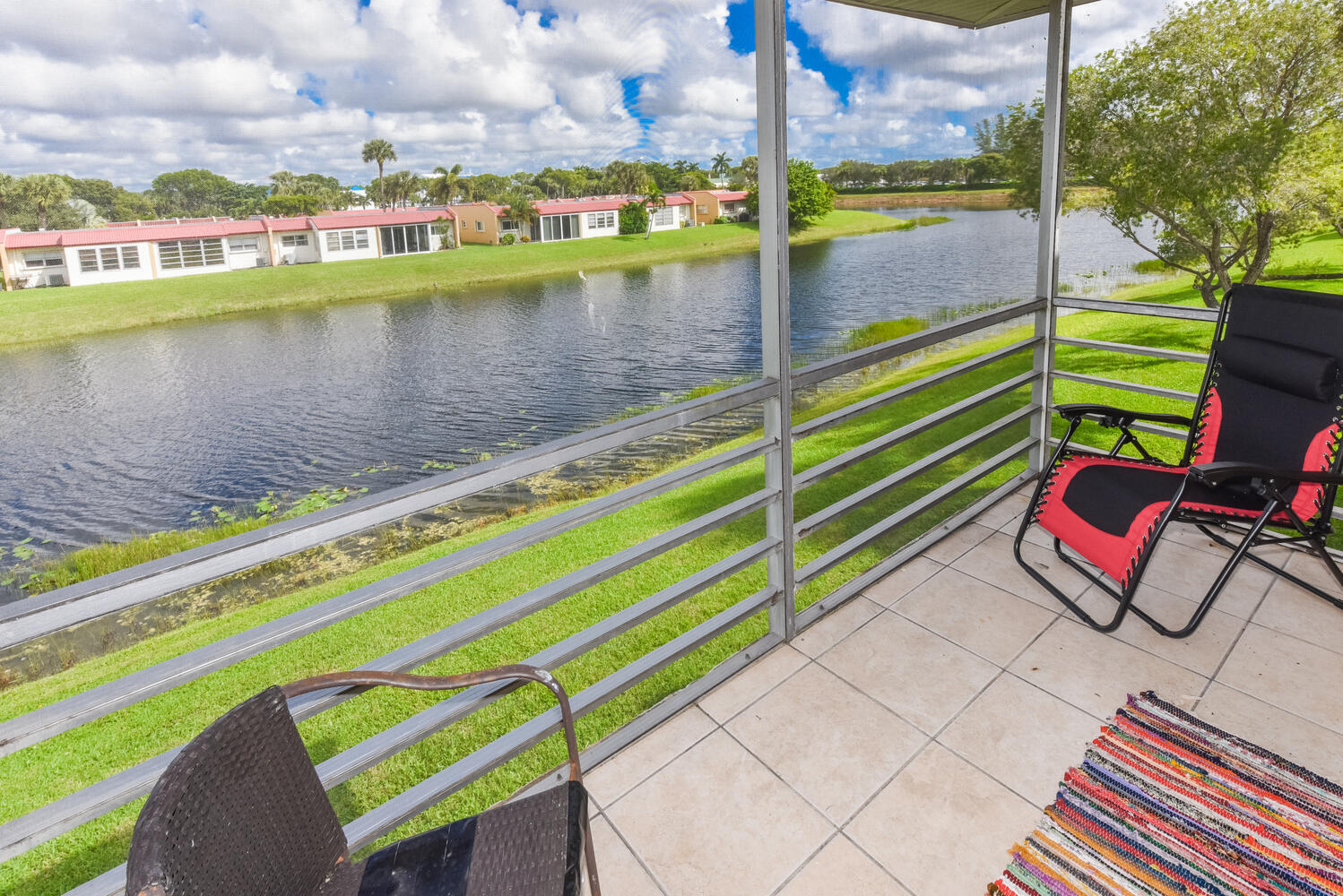 477 Lake Dora Drive West Palm Beach, FL 33411 - Photo 26 of 28 a view of a lake with a bench and a floor to ceiling window
