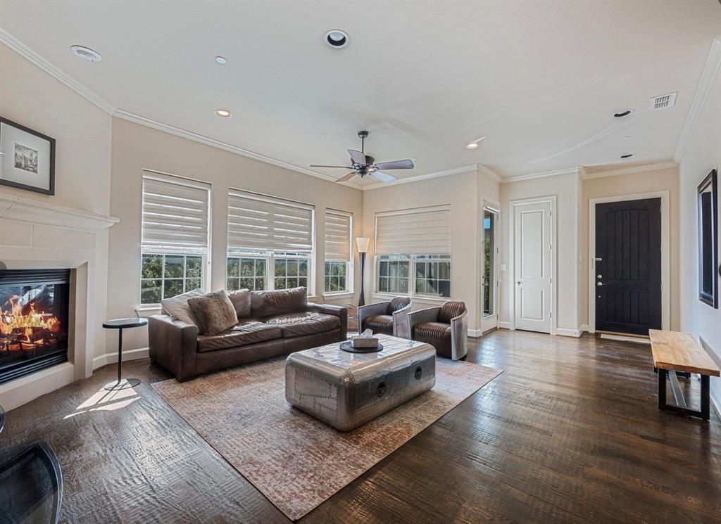 5001 Meridian Lane, Unit 2103 Addison, TX 75001 - Photo 4 of 26 Spacious living area featuring dark wood flooring, a fireplace with a stone surround, multiple windows with blinds, crown molding, and recessed lighting