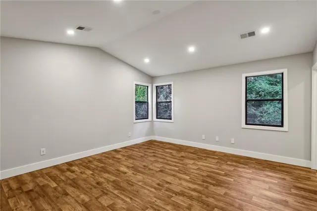 a spacious bedroom with a bed and wooden floor