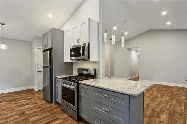 a kitchen with granite countertop a sink cabinets and stainless steel appliances