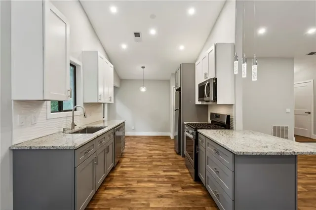 a large kitchen with stainless steel appliances granite countertop a sink and cabinets