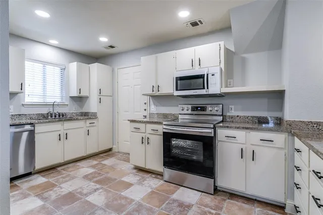 a kitchen with granite countertop white cabinets white stainless steel appliances and a sink
