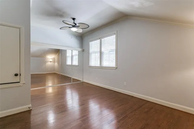 an empty room with wooden floor fan and windows