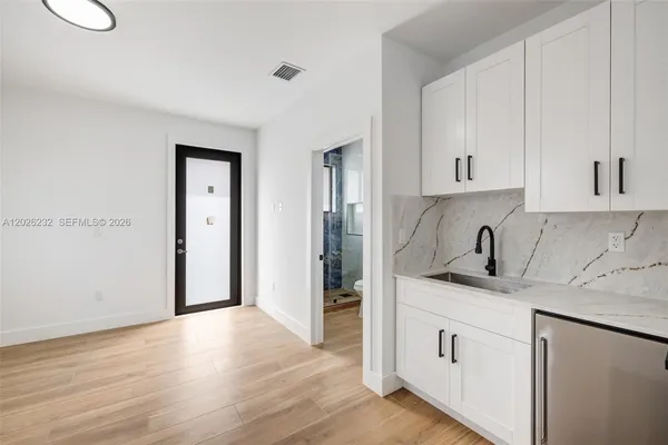a kitchen with white cabinets and sink