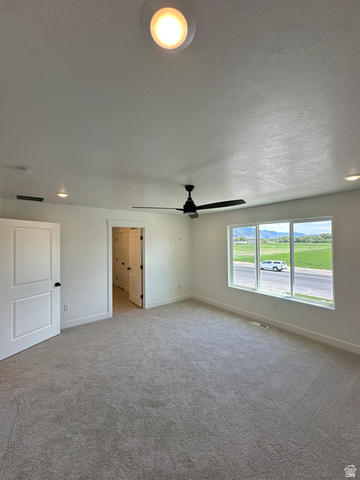 1225 West 500 South Logan, UT 84321 - Photo 31 of 39 Spacious room featuring neutral carpeting, a modern black ceiling fan, multiple recessed lights, and a large window offering expansive outdoor scenery
