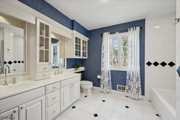 a spacious bathroom with a double vanity sink a toilet and a bathtub