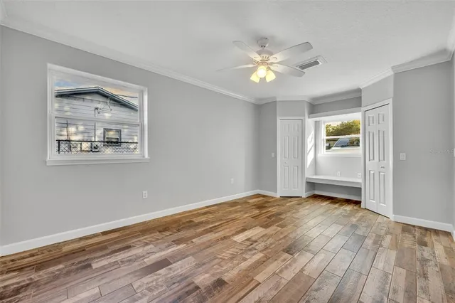 a view of an empty room with wooden floor and a window