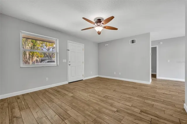a view of an empty room with wooden floor and window