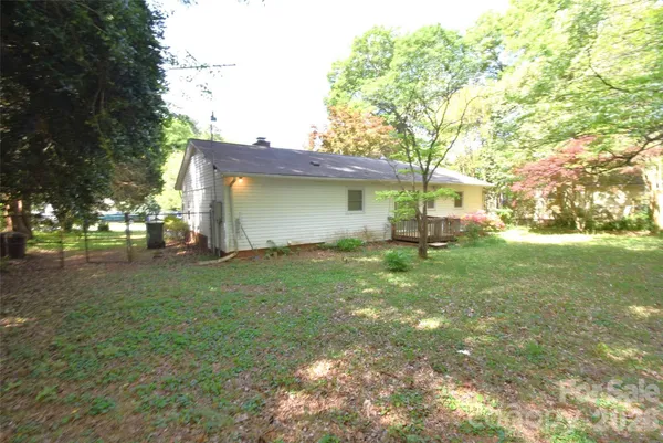 a backyard of a house with plants and large tree
