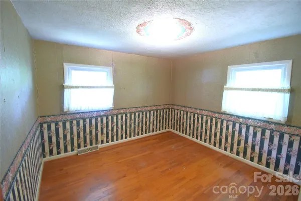 a view of a hallway with wooden floor and a bathroom