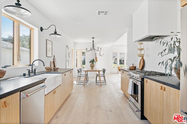 a large kitchen with stainless steel appliances a stove a sink dishwasher and cabinets with wooden floor