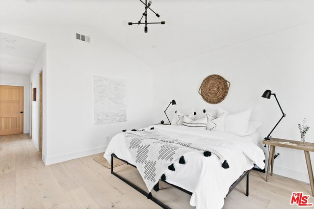 a bedroom with a bed a clock and white walls