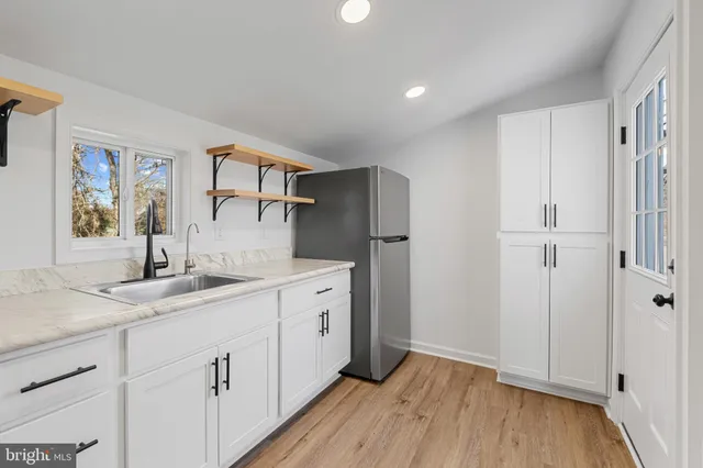 a kitchen with white cabinets and wooden floor