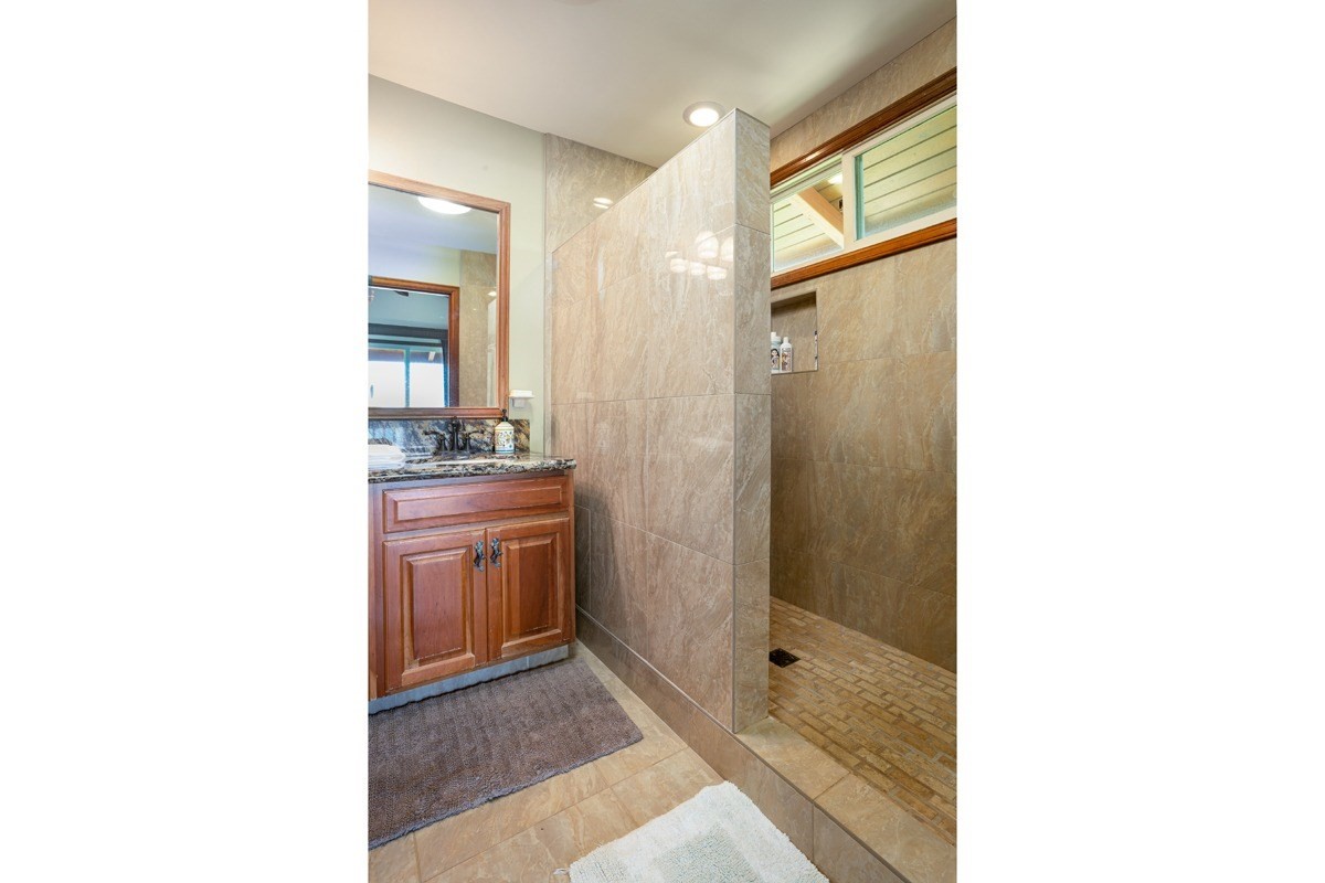 1871 Pe'e Road, Unit 2 Koloa, HI 96756 - Photo 12 of 25 a bathroom with a granite countertop sink a mirror and shower