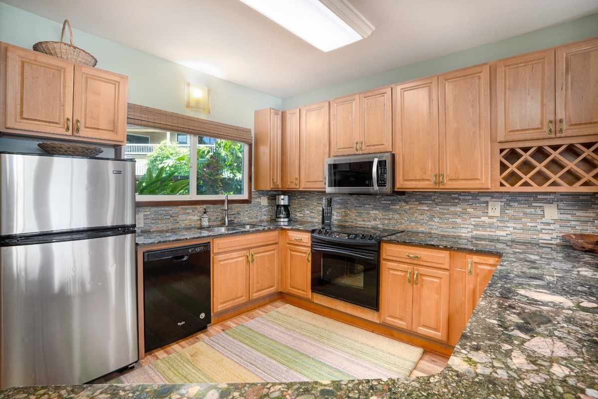 1871 Pe'e Road, Unit 2 Koloa, HI 96756 - Photo 6 of 25 a kitchen with stainless steel appliances granite countertop a refrigerator stove microwave sink and cabinets