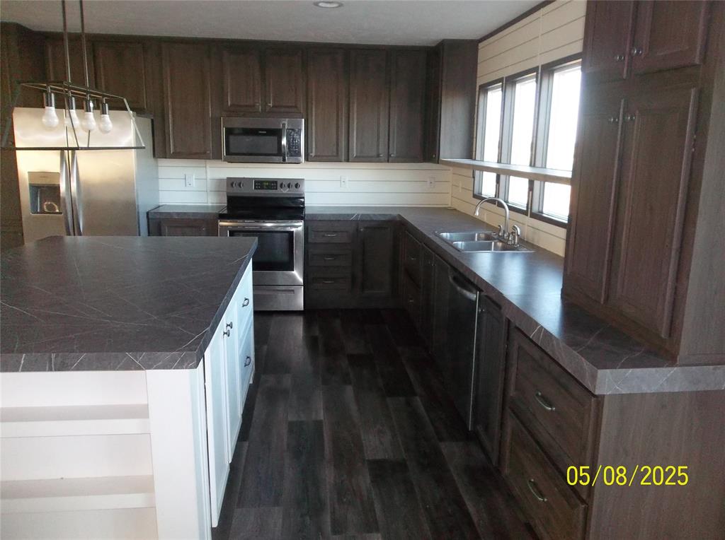 531 Blair Road Waxahachie, TX 75165 - Photo 20 of 40 Kitchen featuring dark countertops, stainless steel appliances, hanging light fixtures, dark wood-style flooring, and dark wood finish cabinetry