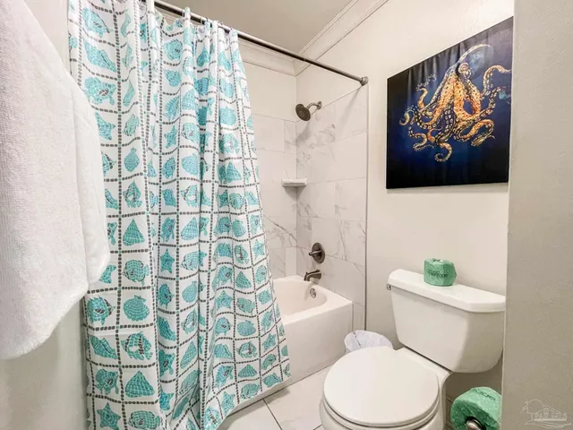 a white toilet sitting next to a bathroom sink and a shower curtain