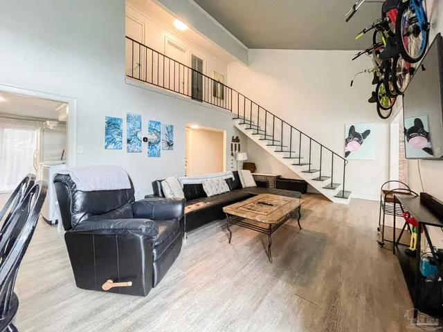 a living room with furniture stairs and a wooden floor