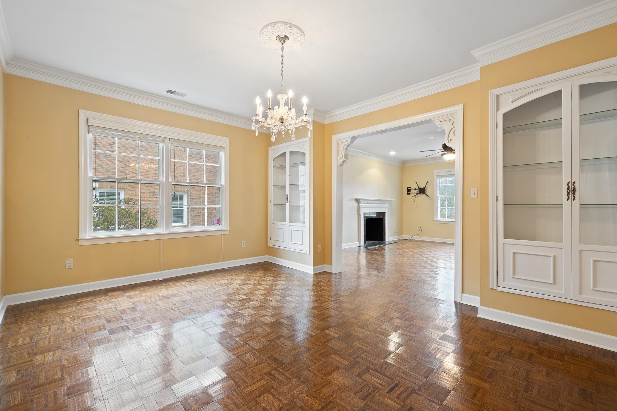 1683 Kimbrough Road Germantown, TN 38138 - Photo 7 of 34 Unfurnished dining area featuring a fireplace, hanging lights, ornamental molding, parquet flooring, and a ceiling fan