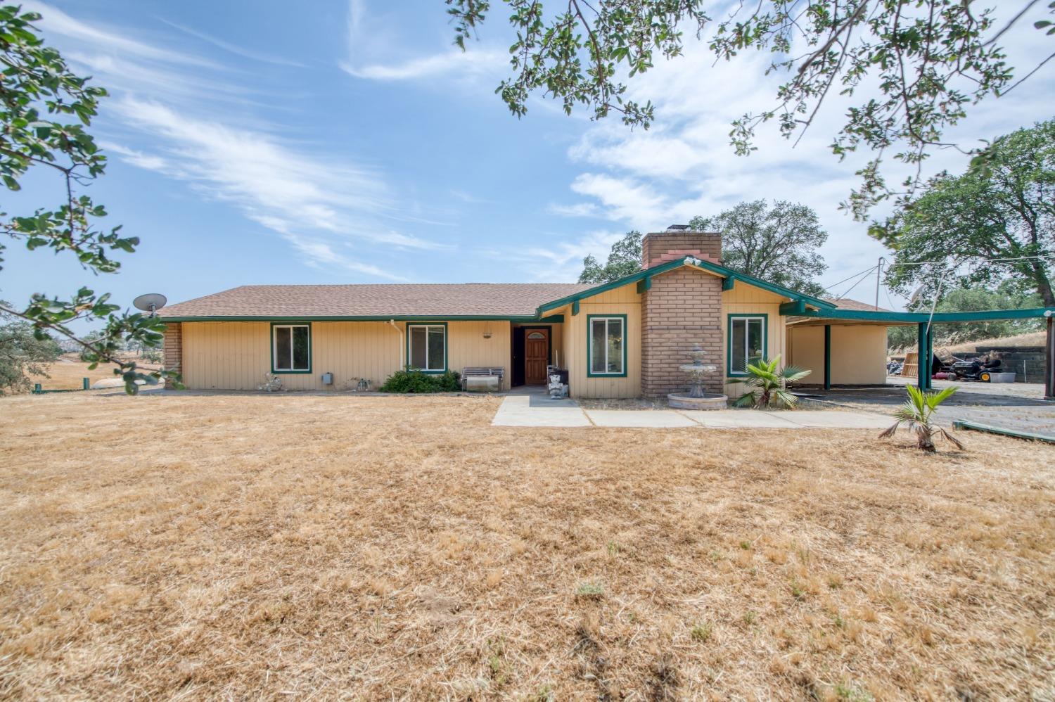 a front view of house with yard and trees in the background