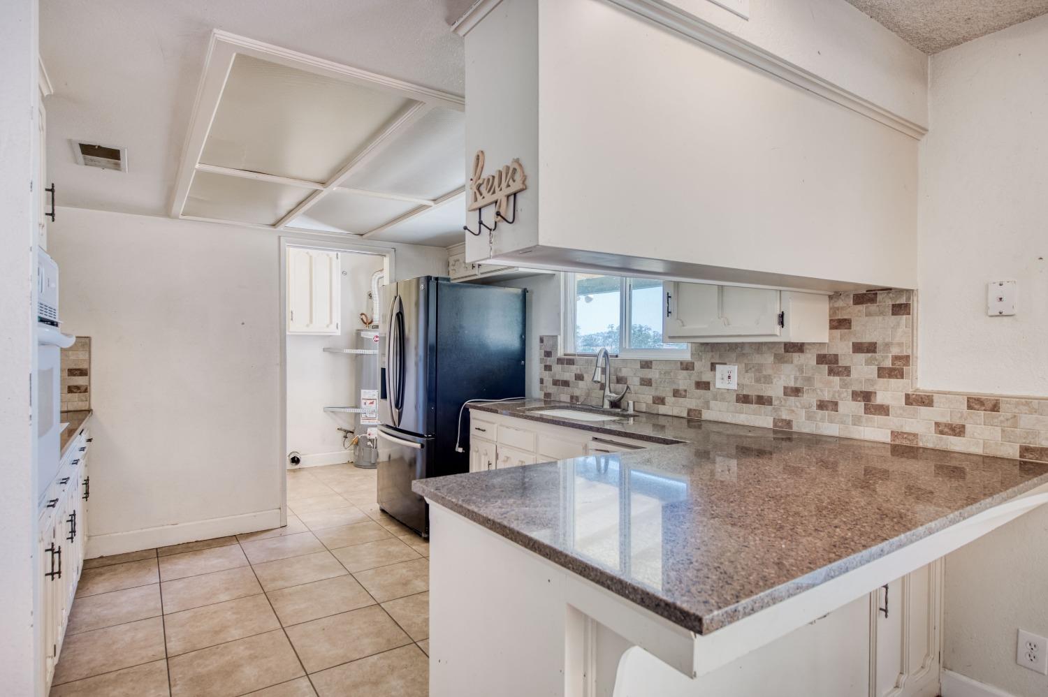 22452 Goldrush Lane Clovis, CA 93619 - Photo 14 of 36 a kitchen with kitchen island a counter top space a sink and cabinets
