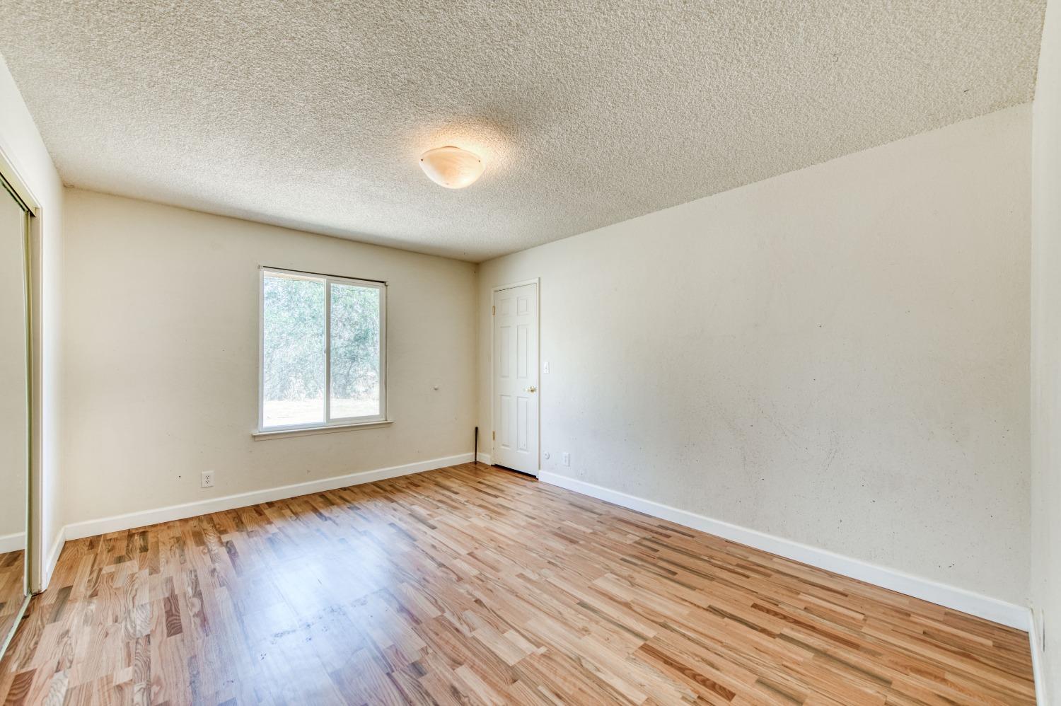 22452 Goldrush Lane Clovis, CA 93619 - Photo 17 of 36 an empty room with wooden floor and windows