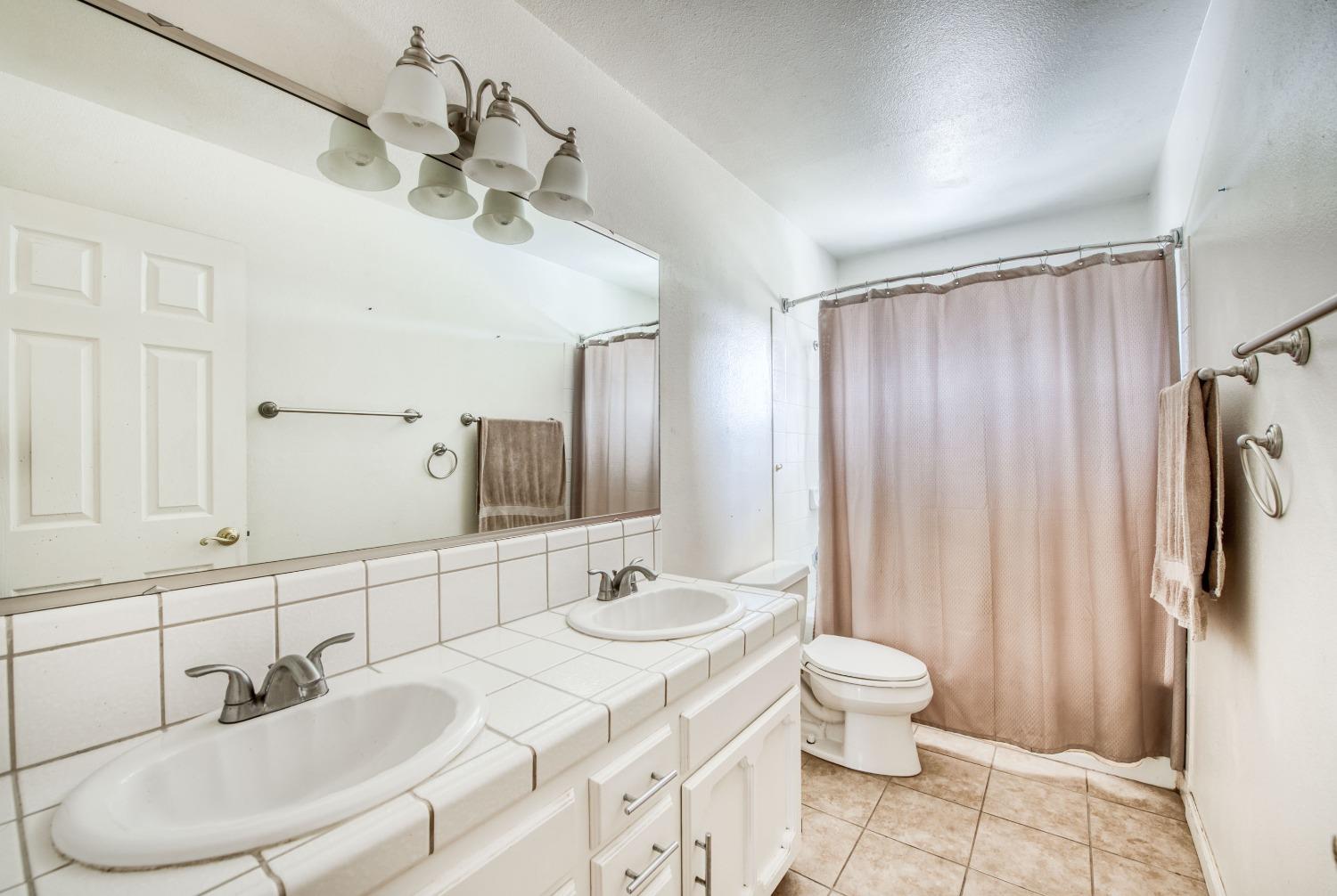 22452 Goldrush Lane Clovis, CA 93619 - Photo 19 of 36 a bathroom with a sink a toilet and shower