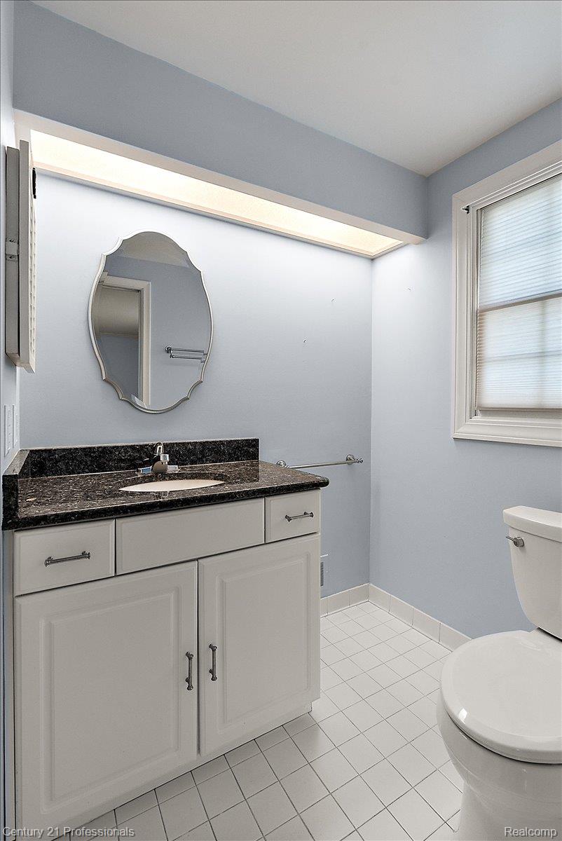 633 Foxhall Road Bloomfield Hills, MI 48304 - Photo 45 of 61 Bathroom featuring a white vanity with paneling and dark countertop, white square floor tiles, and a window with blinds