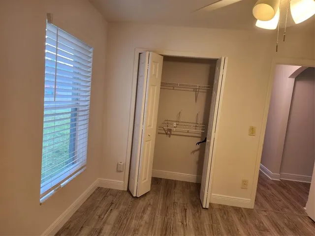 a view of an empty room with wooden floor and a window