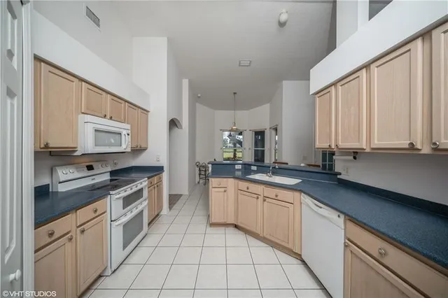 a kitchen with stainless steel appliances granite countertop a sink and dishwasher a stove top oven with white cabinets