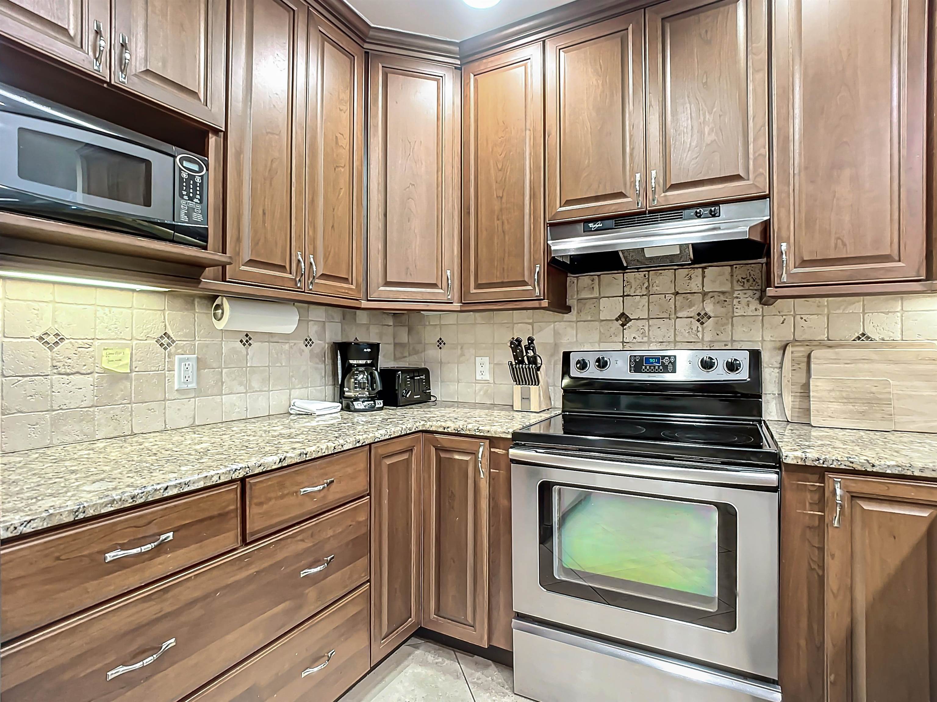931 A1A Beach Boulevard, Unit 306 St. Augustine, FL 32080 - Photo 20 of 47 a kitchen with granite countertop cabinets stainless steel appliances and a sink