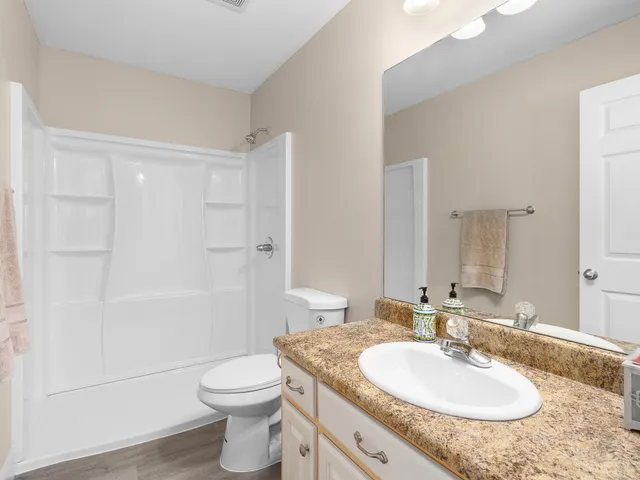 a bathroom with a granite countertop sink toilet a mirror and shower