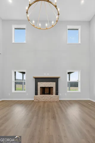 a view of an empty room with wooden floor and a kitchen