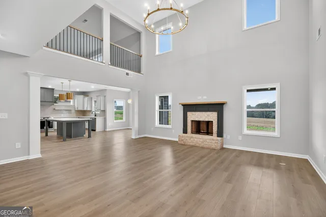 a kitchen with stainless steel appliances kitchen island granite countertop a refrigerator oven a sink dishwasher and white cabinets with wooden floor