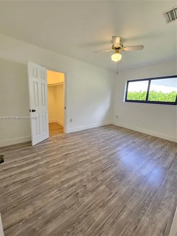 a view of empty room with wooden floor and fan