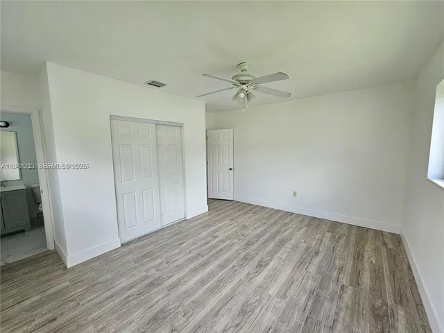 an empty room with wooden floor and ceiling fan