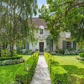 a view of a house with a small yard plants and large trees