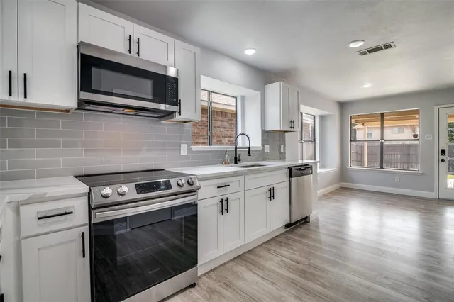 a kitchen with stainless steel appliances a stove microwave and sink