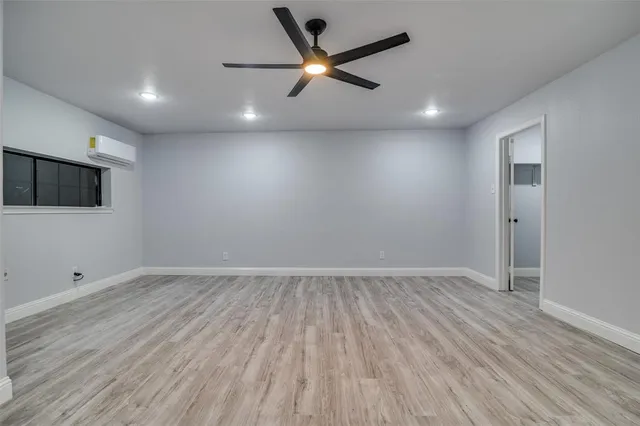 an empty room with wooden floor and a ceiling fan