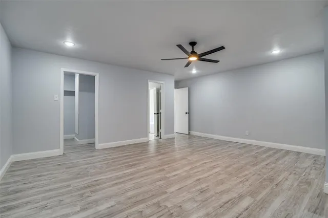 an empty room with wooden floor and a ceiling fan
