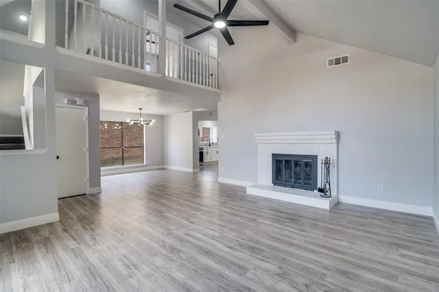 a view of an empty room with wooden floor and a fireplace